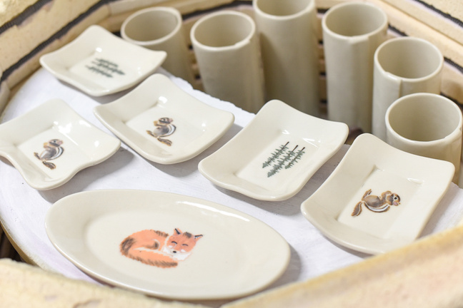 Glazed handmade pottery in a kiln. The pottery features various designs inspired by nature.